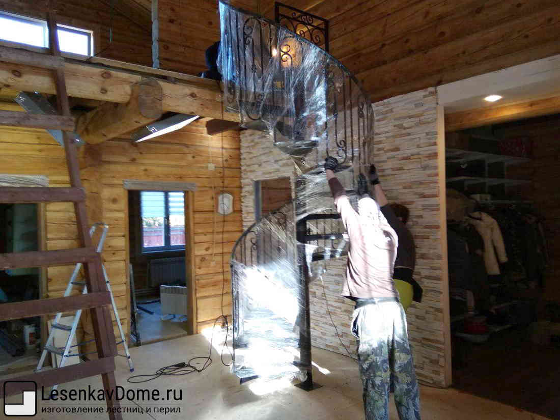 Винтовая лестница из металла в процессе монтажа в деревянном доме